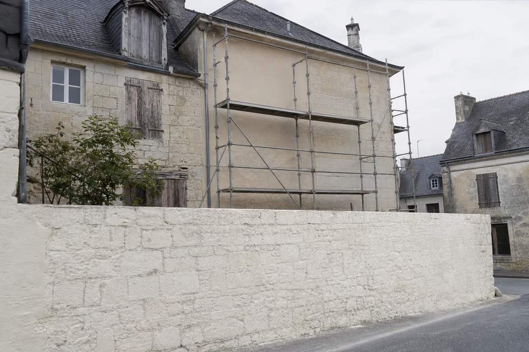 Façade de maison de ville en tuffeau blond sous échafaudage, enduit repris sur une partie