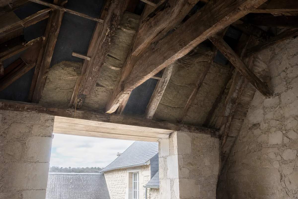 Pose d’un isolant en rouleau entre chevrons dans des combles, sur un de nos chantiers