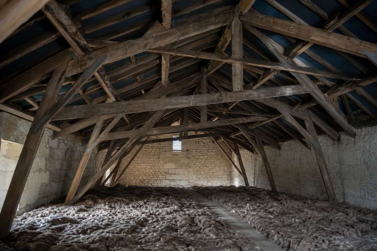 Combles sous charpente industrielle en fermettes, entretoises visibles, avant aménagement