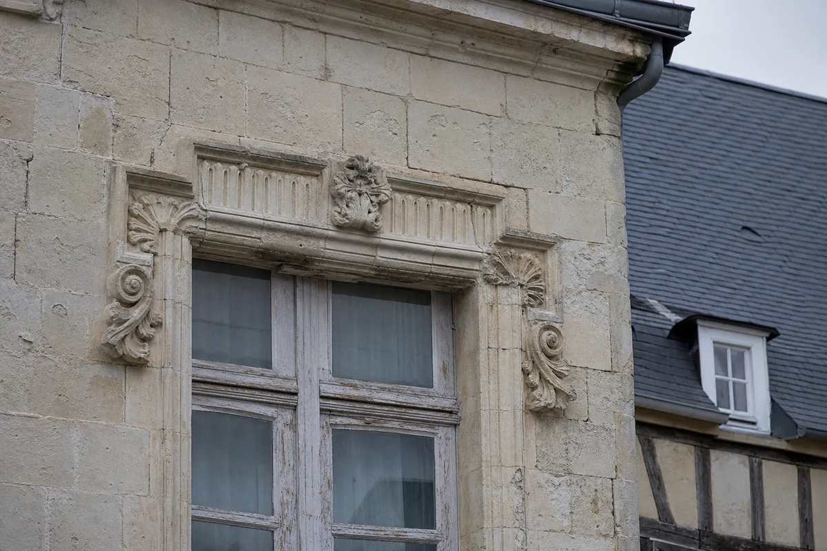 Détail de façade lavalloise : tuffeau farinant, encadrement de baie en pierre et menuiserie ancienne à repeindre