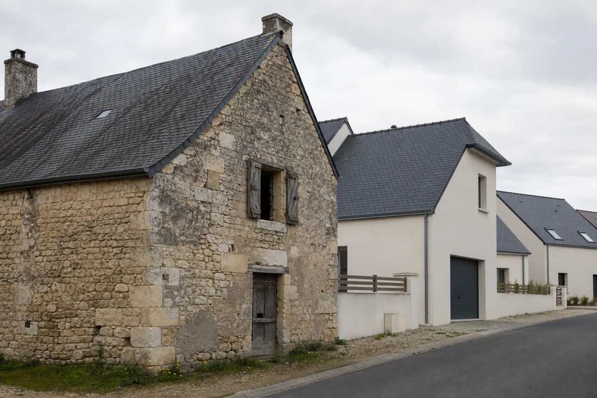 Rue de bourg mayennais mêlant maisons anciennes et constructions récentes