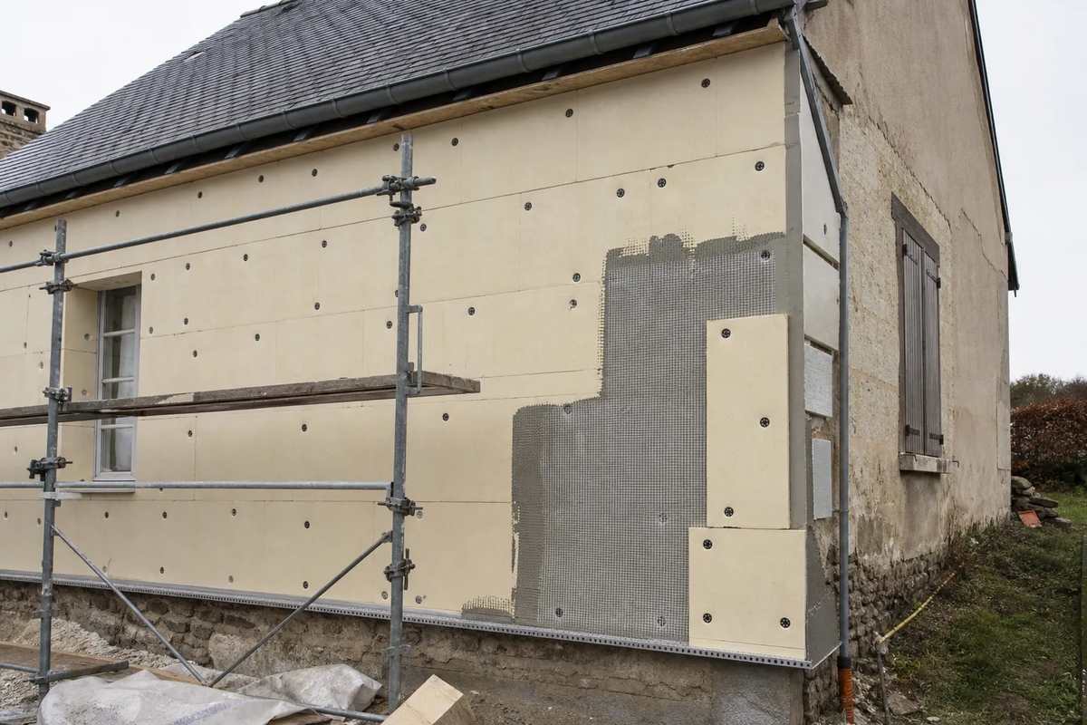 Pose d’une isolation par l’extérieur sur un pignon : panneaux, rail de départ et angle en cours